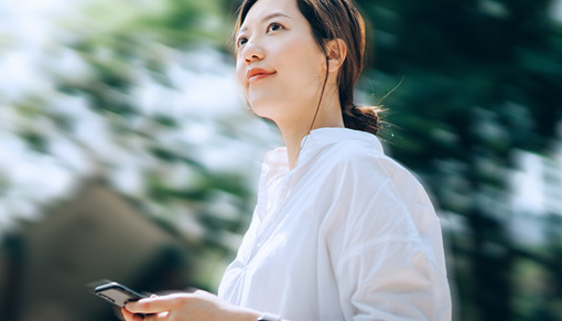 Femme marchant dans un parc avec son téléphone portable à la main