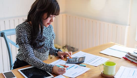 femme assise sur un bureau, faisant des feuilles de comptabilité