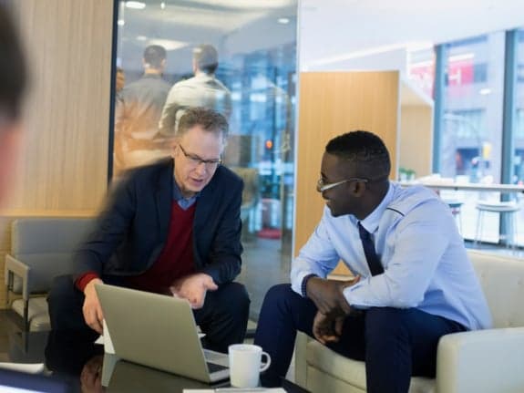 deux hommes d'affaires souriant et parlant tout en regardant un ordinateur portable